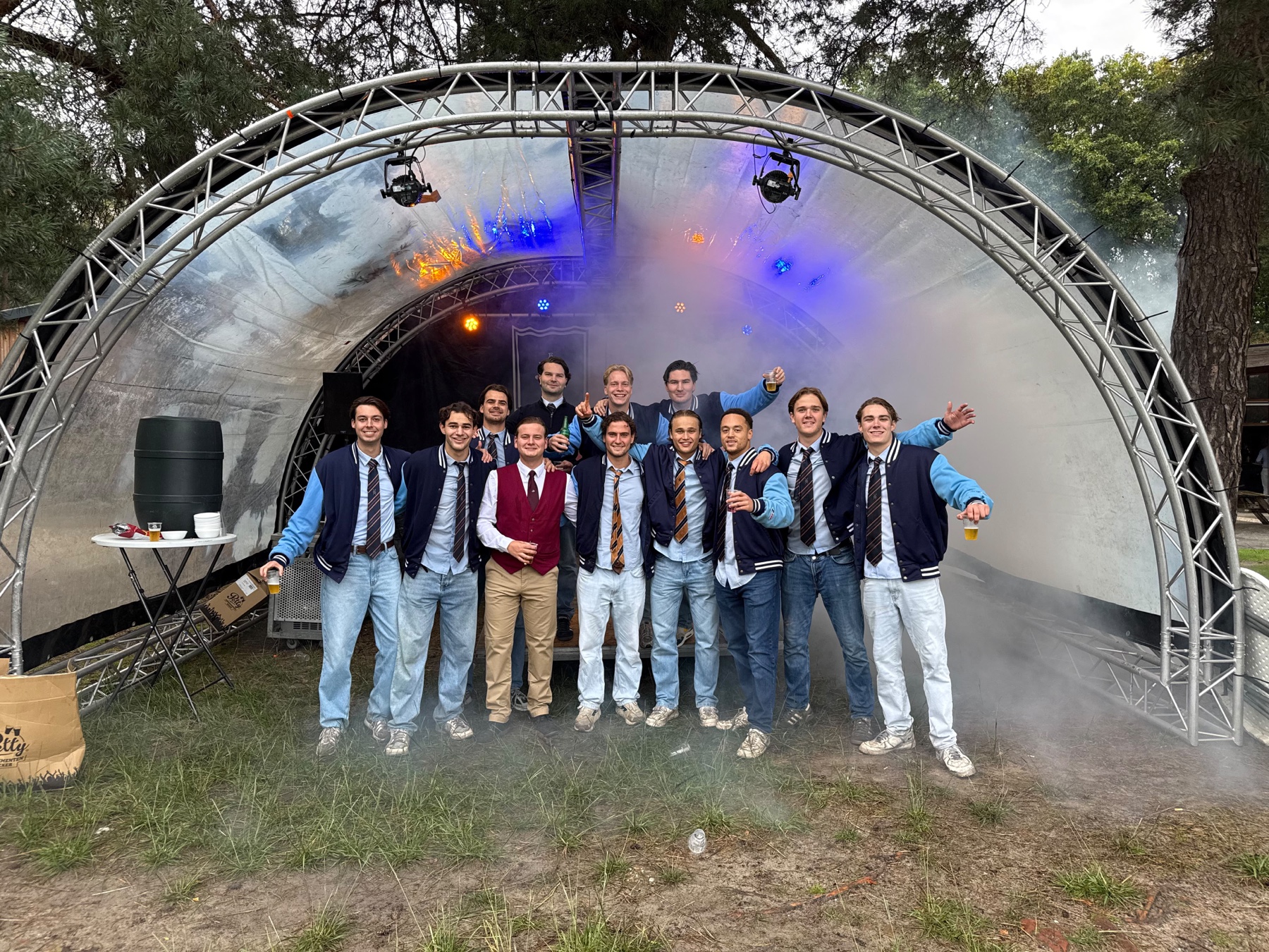 P.E.B.-leden in jasje en das bij een podium tijdens de disputenronde