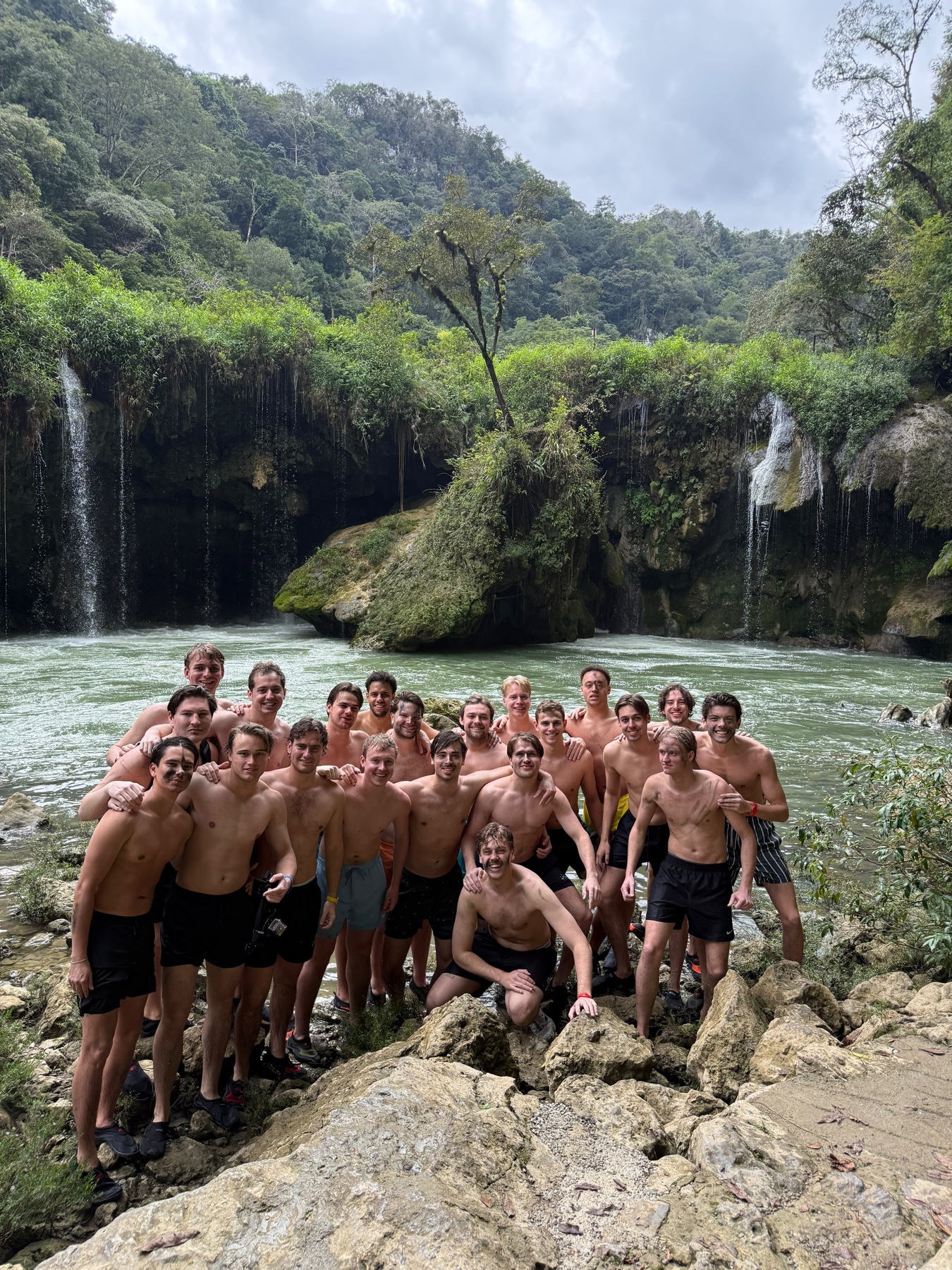 P.E.B.-leden samen op de rotsen voor een waterval